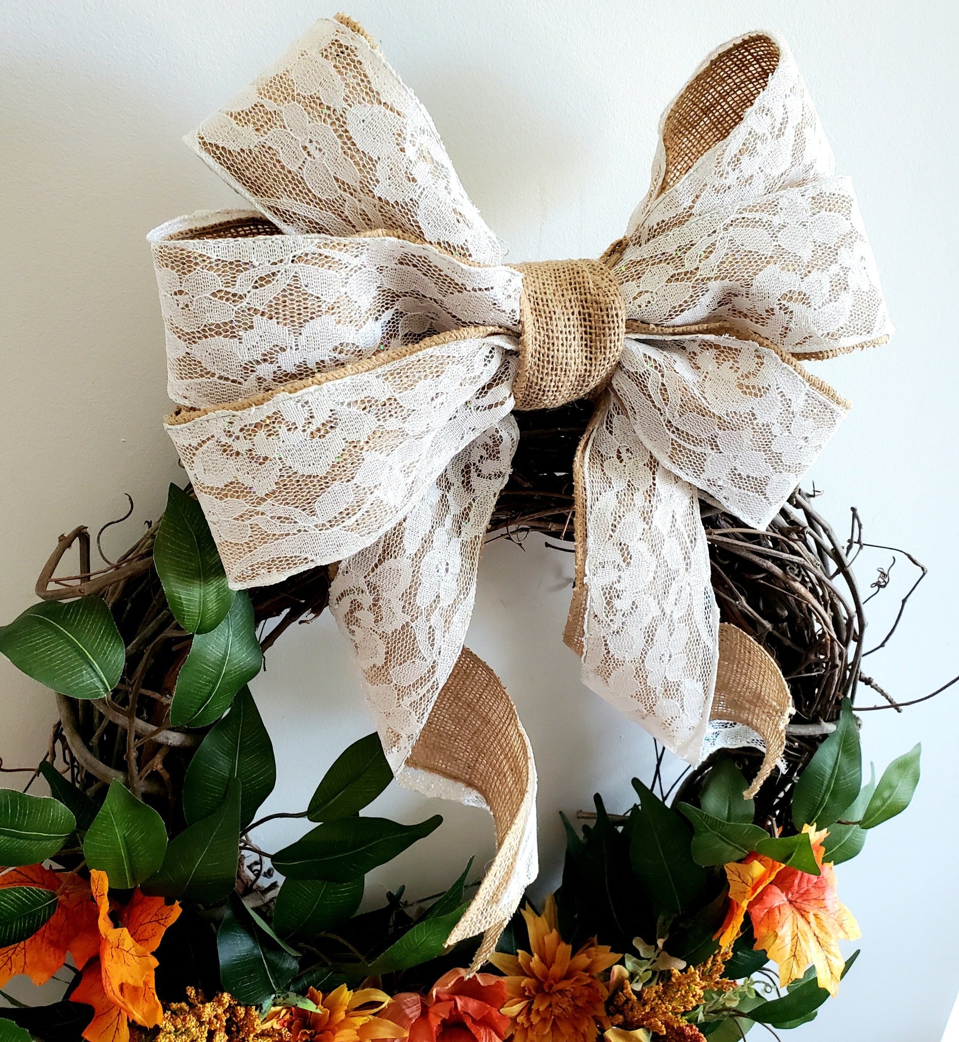 burlap and lace bow on top of a decorative fall wreath